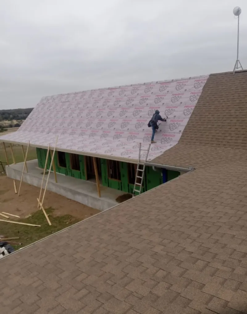Worker preparing underlayment for a metal roof installation in Hopkinton